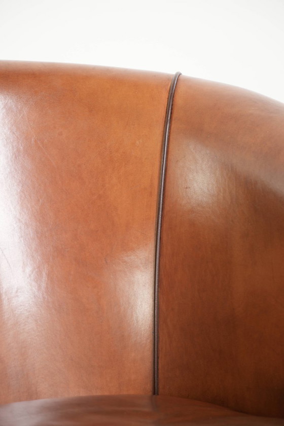 Image 1 of Vintage schapenleren clubfauteuil met een warme kleurstelling en afgewerkt met zwarte biezen