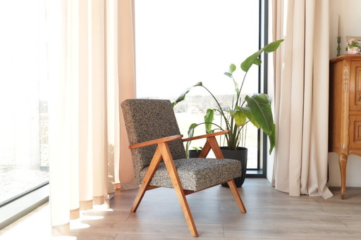 Poltrona lounge dal design vintage in tessuto mélange nero e legno color noce.