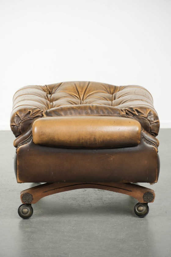 Image 1 of Exclusivo y elegante puf inglés Chesterfield de piel de vacuno con ruedas y acabado con clavos decorativos.
