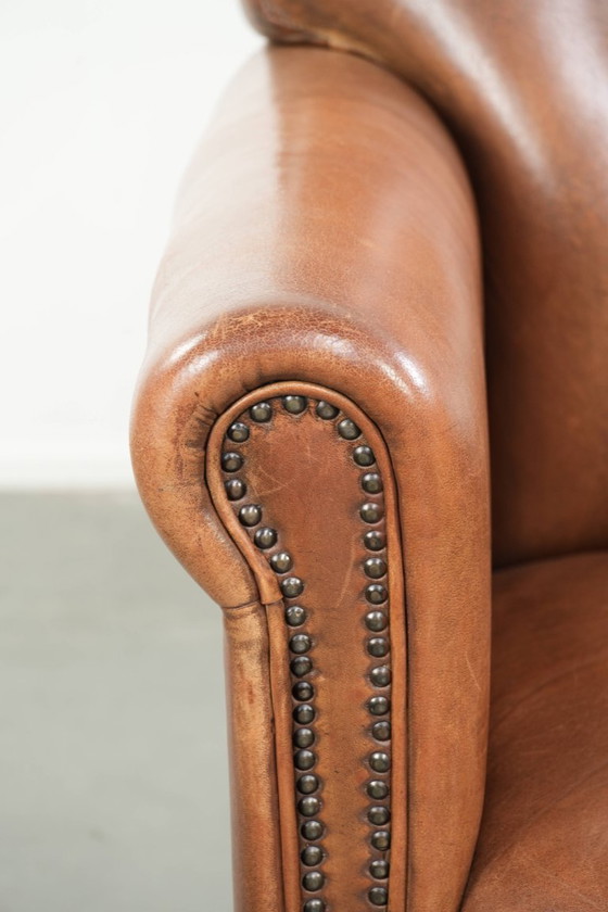 Image 1 of Fauteuil en bon état, en peau de mouton avec une finition raffinée et des clous décoratifs.