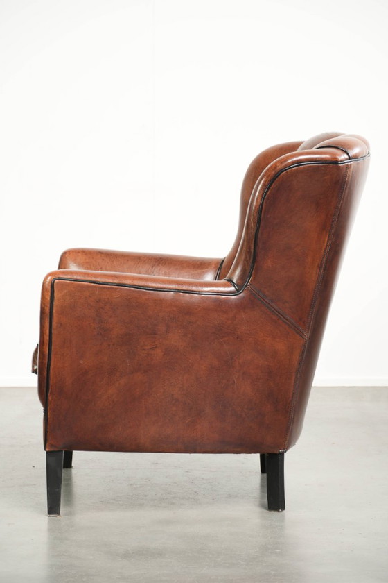 Fauteuil unique en peau de mouton aux couleurs chaudes et profondes, orné d'un passepoil noir. – Leather (photo 5 of 14)