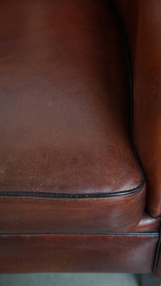 Image 1 of Sillón club de piel de oveja en un color cálido y profundo y acabado con ribete negro.