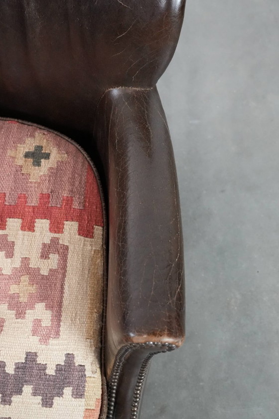 Image 1 of Subtiele donkerbruine fauteuil gemaakt van rundleer met een omkeerbaar Kelim zitkussen