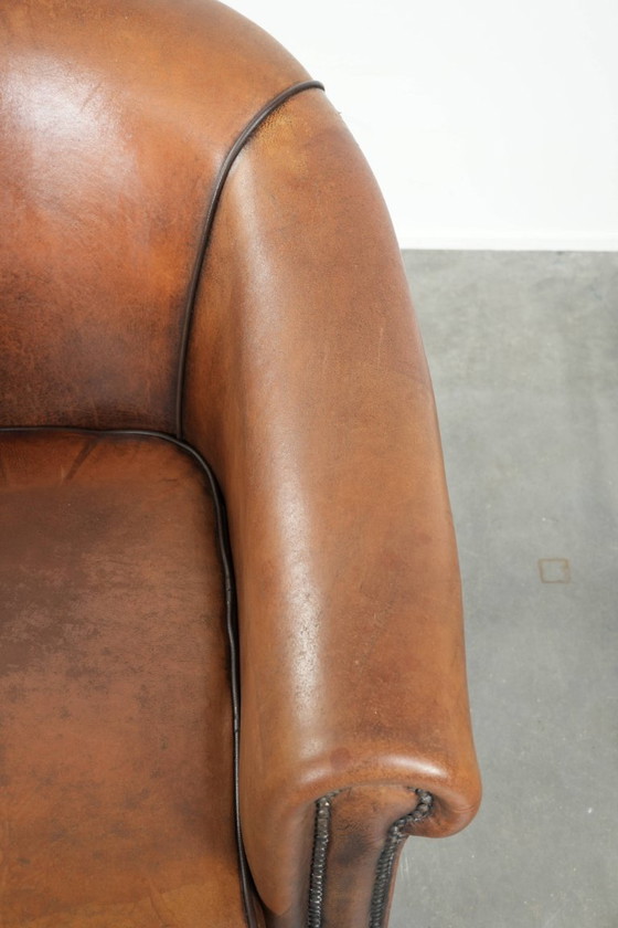 Image 1 of Schapenleren clubfauteuil met een mooie patina en een verfijnde afwerking met zwarte biezen