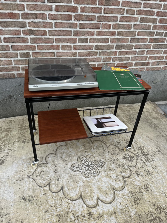 Image 1 of Mueble estéreo antiguo de teca con estructura de metal negro y ruedas giratorias.