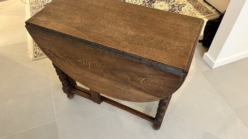 Mesa plegable de roble macizo estilo neojacobino inglés con patas abatibles.
Circa 1925–1940