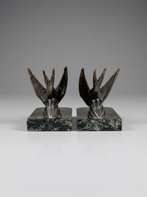 Image 1 of Een paar art-deco boekensteunen – zwaluwen van gepatineerd zink op groene marmeren voetstukken.