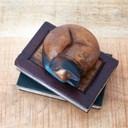 Figura de teca de un gato durmiendo sobre dos libros.