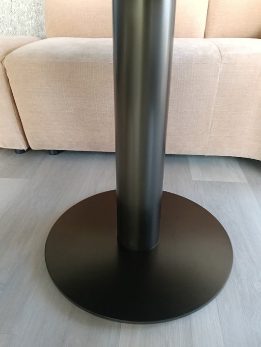 Mesa de comedor con tablero de cerámica mate y patas de bronce.