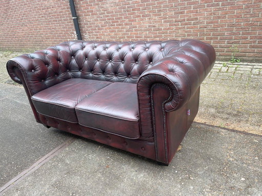 Sofá Chesterfield inglés de cuero color burdeos.