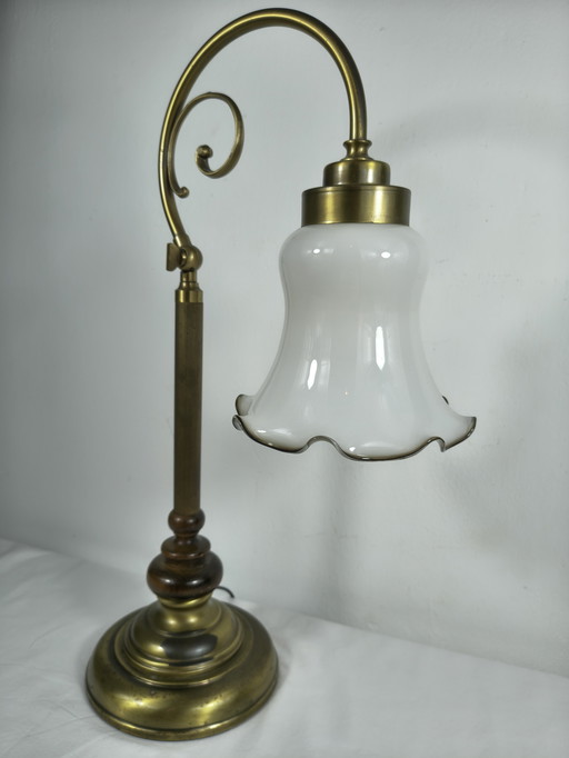 Lámpara de mesa vintage de latón con pantalla de cristal opalino y brazo decorativo clásico.