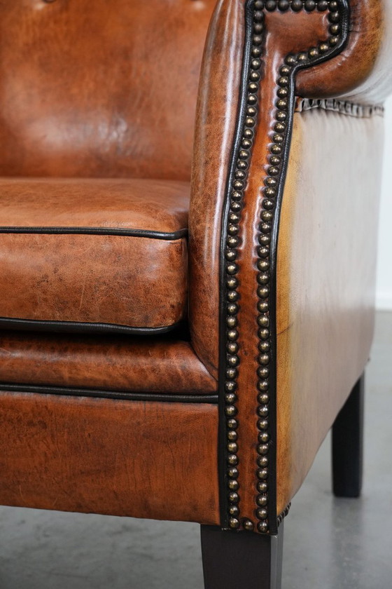 Image 1 of Grote schapenleren oorfauteuil met zwarte biezen en siernagels