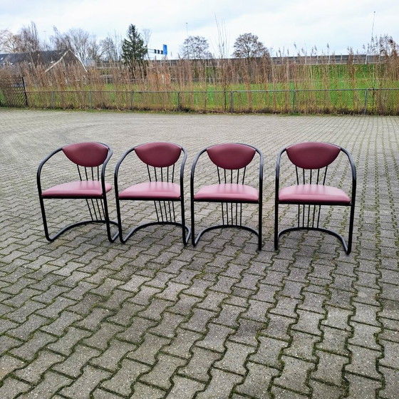 Image 1 of This is a set of four vintage 'Memphis' style chairs with a black metal frame and burgundy upholstery.