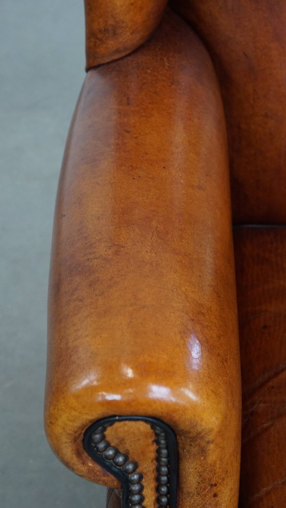 Image 1 of Comfortabele schapenleren oorfauteuil met een prachtige warme kleurstelling en een afwerking met stiksels en zwarte biezen