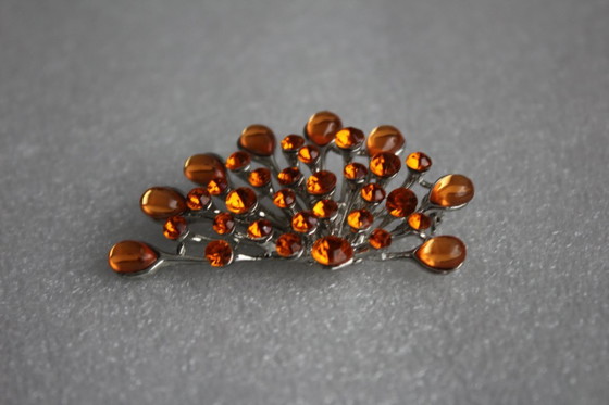 Image 1 of Gebogen broche met honingkleurige glazen steentjes op een zilverkleurig metalen frame, vintage uit de jaren 80.