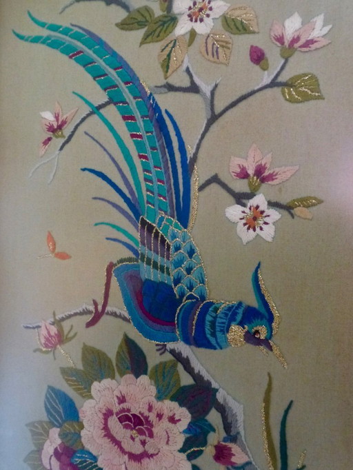 Vintage hand-embroidered wall tapestry, behind glass, with a crane, butterflies and flowers.