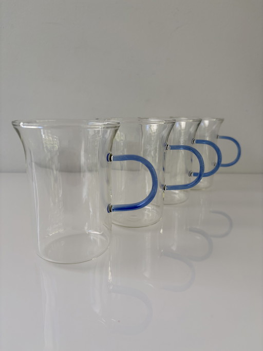 Juego de cuatro tazas de té de cristal con asas de colores.