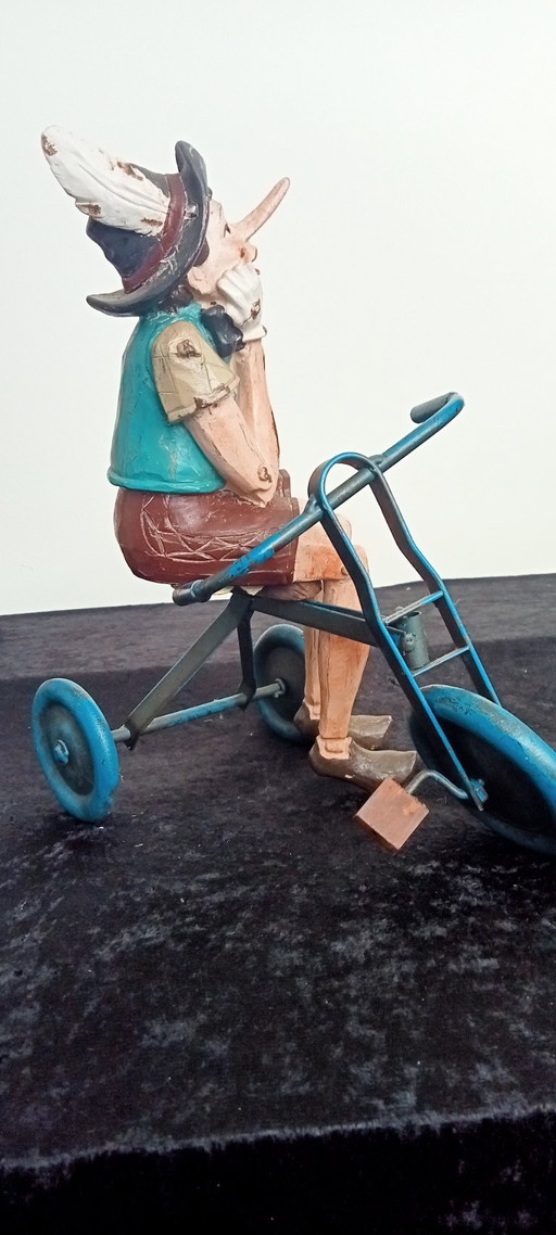 Objet de collection : Statue artisanale de Pinocchio sur un tricycle