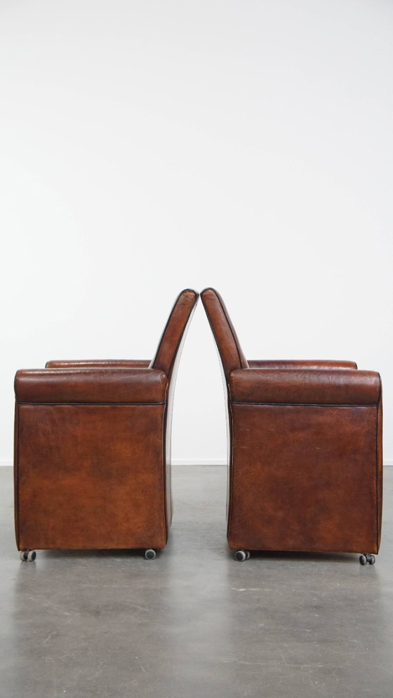Image 1 of 2 x Vintage schapenleren eetkamerstoel met zwarte biezen op wieltjes