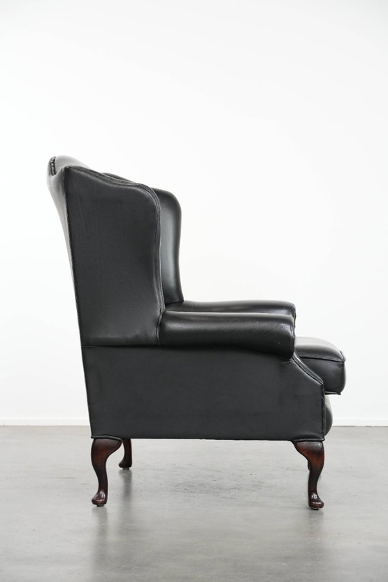 Image 1 of Smooth black cowhide Chesterfield wingback armchair in English style with color-matched piping