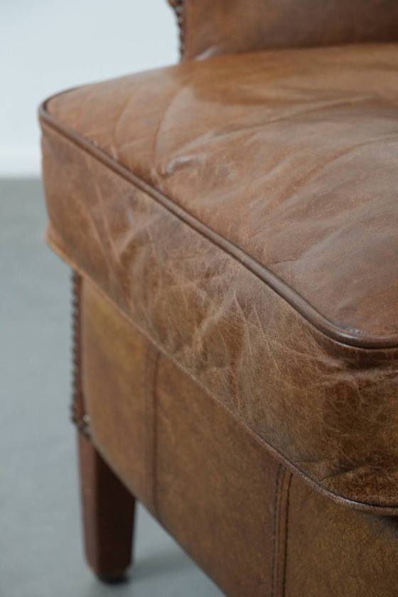Image 1 of Tijdloze cognac kleurige oorfauteuil in Engelse stijl gemaakt van rundleer afgewerkt met siernagels
