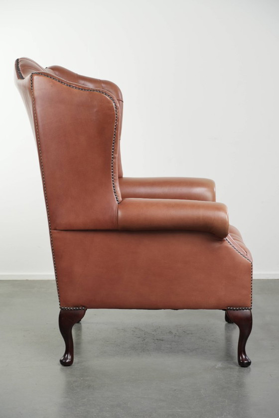 Image 1 of Fauteuil Chesterfield à oreilles en cuir de vachette anglais, assise capitonnée, avec une belle patine et de jolies couleurs.