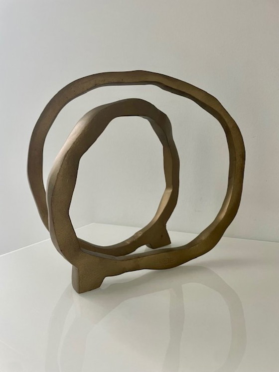 Image 1 of Escultura de diseño con forma de anillo abierto en oro mate.