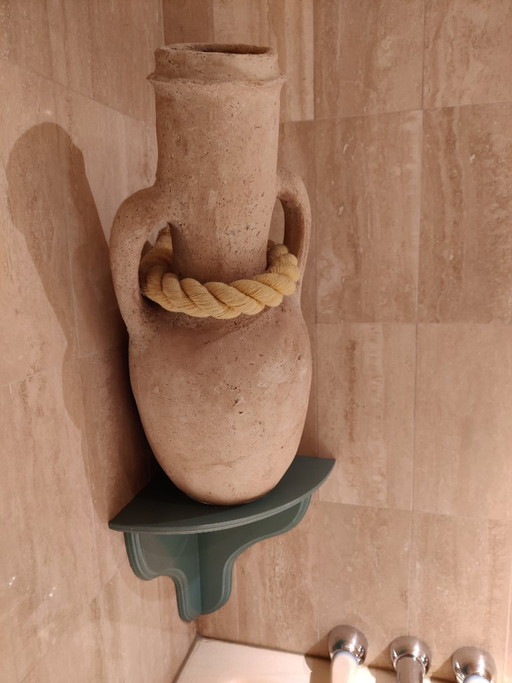 Beige terracotta amfora inclusief houten ondersteuningsbevestiging en dik touw om schuin op te hangen.