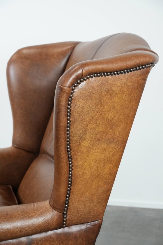 Image 1 of Tijdloze cognac kleurige oorfauteuil in Engelse stijl gemaakt van rundleer afgewerkt met siernagels