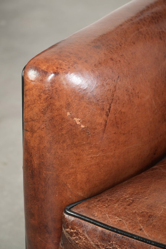 Fauteuil unique en peau de mouton aux couleurs chaudes et profondes, orné d'un passepoil noir. – Leather (photo 10 of 14)