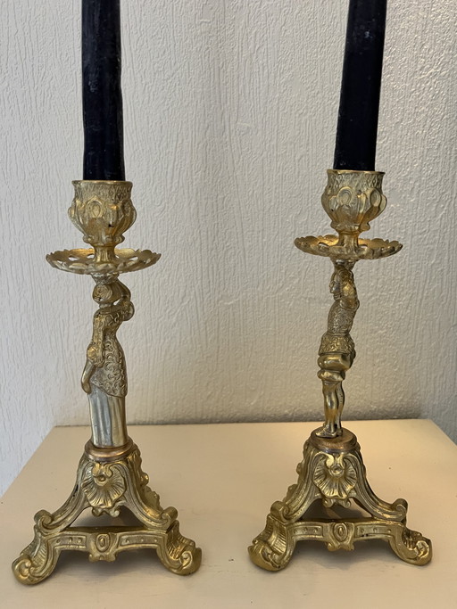 Een paar bronzen kandelaars in Empirestijl met een vrouwelijk en een mannelijk beeldje.