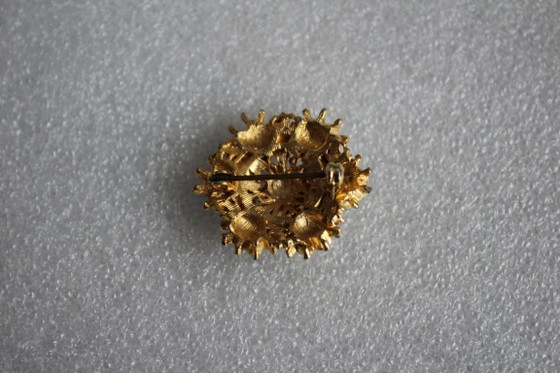 Image 1 of Ronde vintage broche, goudkleurig metaal met kleine groene en witte parels.