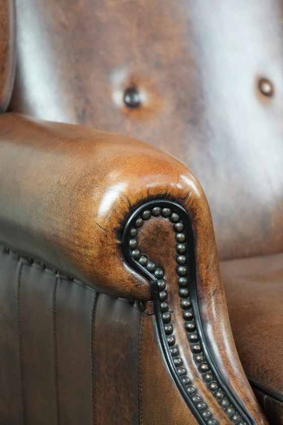 Image 1 of Comfortabele en tijdloze schapenleren oorfauteuil met siernagels en zwarte biezen