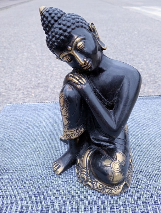 Buddha sculpture, dark with gold-colored accents