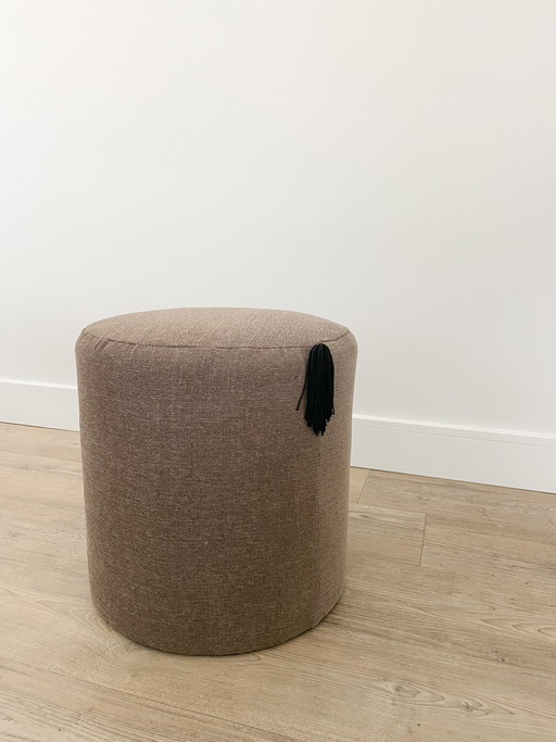 Pouf fatto a mano con dettagli a frange nere.