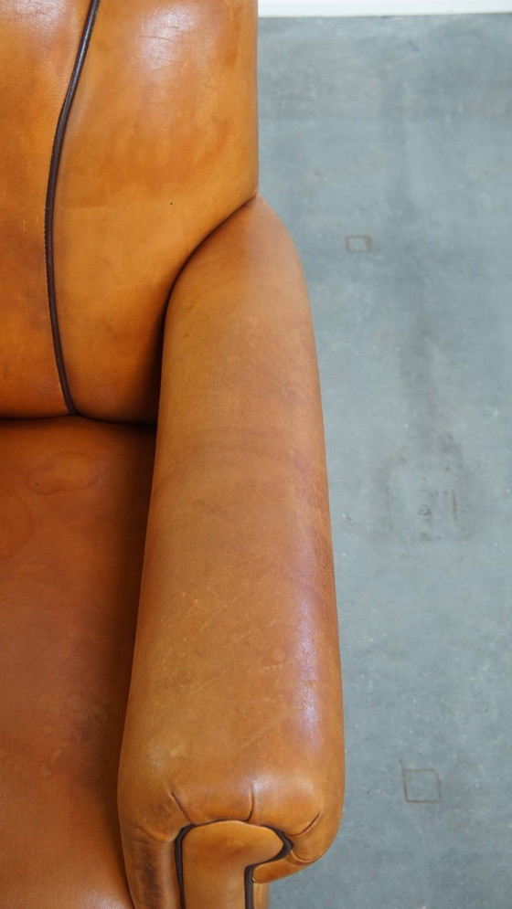 Image 1 of Schapenleren armchair met een afwerking met donkerbruine biezen