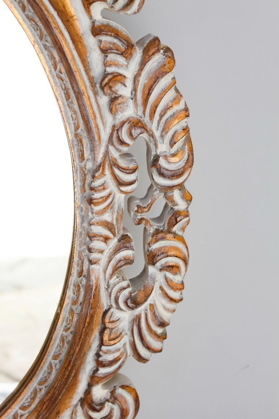 Image 1 of Oval mirror, gilded and carved from wood. Decorated and distressed with scrolls and leaves. Exclusively handmade by artisans.