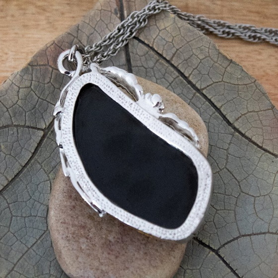 Image 1 of Grande ciondolo in ambra baltica verde: incastonato in metallo color argento con decorazioni floreali.