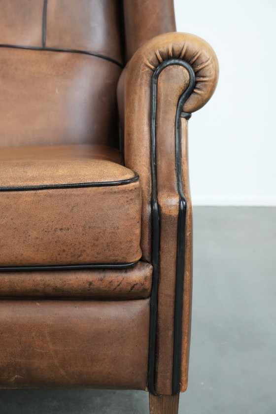 Image 1 of Poltrona a orecchioni in pelle di pecora con profili neri, in buone condizioni.