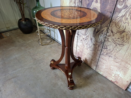 Mesa central redonda clásica de chapa de nogal con marquetería, base ornamentada y herrajes de latón.