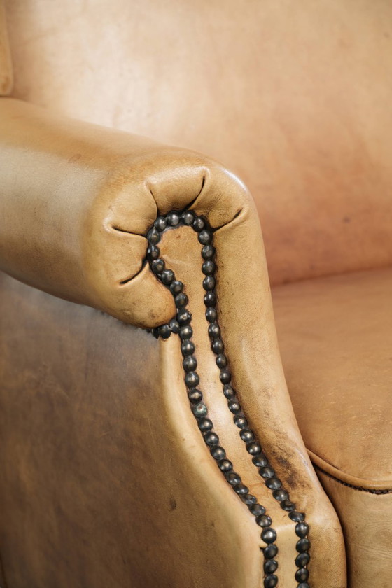 Image 1 of Dos hermosos sillones orejeros de piel de vaca clara con un estilo inglés atemporal y gran comodidad.