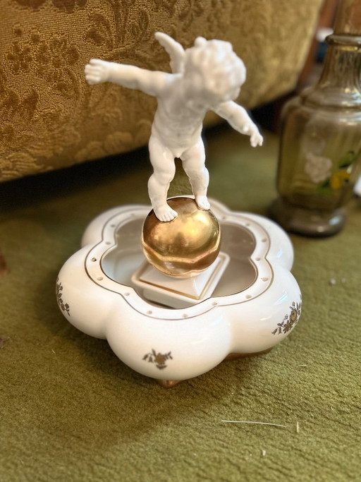 Ángel de porcelana sobre una esfera dorada