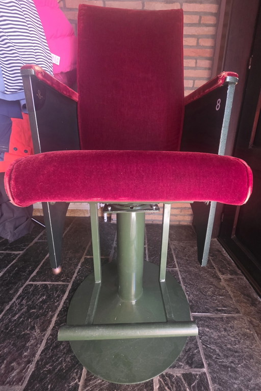 Silla de cine vintage, de terciopelo rojo, con base giratoria verde.