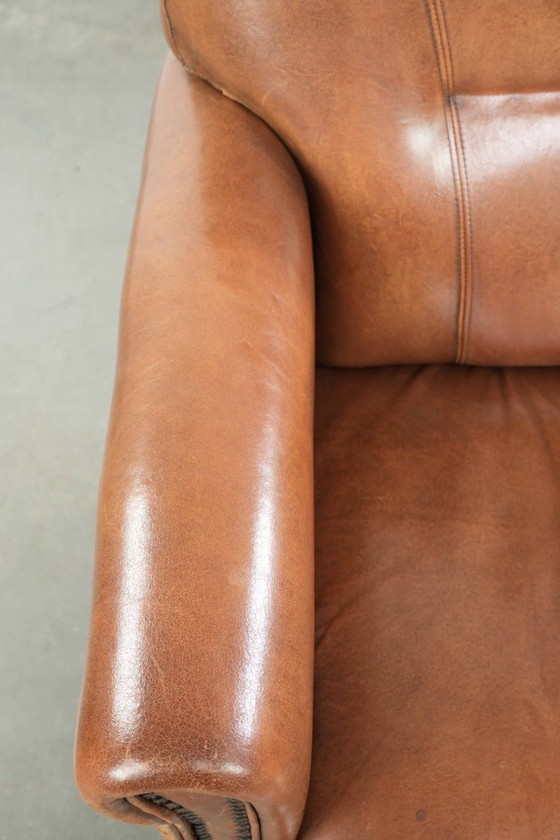 Image 1 of Fauteuil en bon état, en peau de mouton avec une finition raffinée et des clous décoratifs.