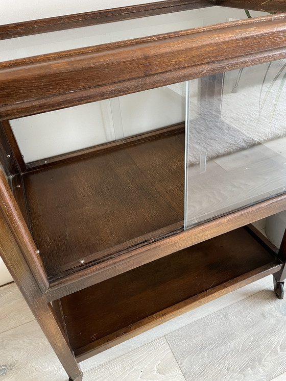 Image 1 of Eikenhouten kast uit het midden van de vorige eeuw met schuifdeuren van glas op wielen (vitrinekast / cocktailkast)