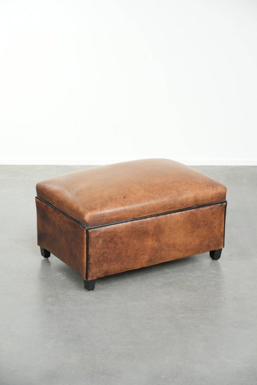 Characterful sheepskin footstool/ottoman with a beautiful patina and finished with black piping.