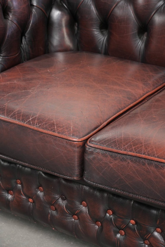 Image 1 of Canapé Chesterfield 2 places en cuir de vachette anglais ancien rouge/marron, au style magnifique et au charme intemporel.