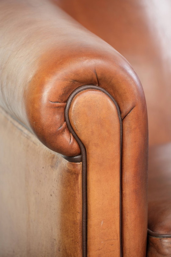Image 1 of Vintage schapenleren clubfauteuil met een warme kleurstelling en afgewerkt met zwarte biezen