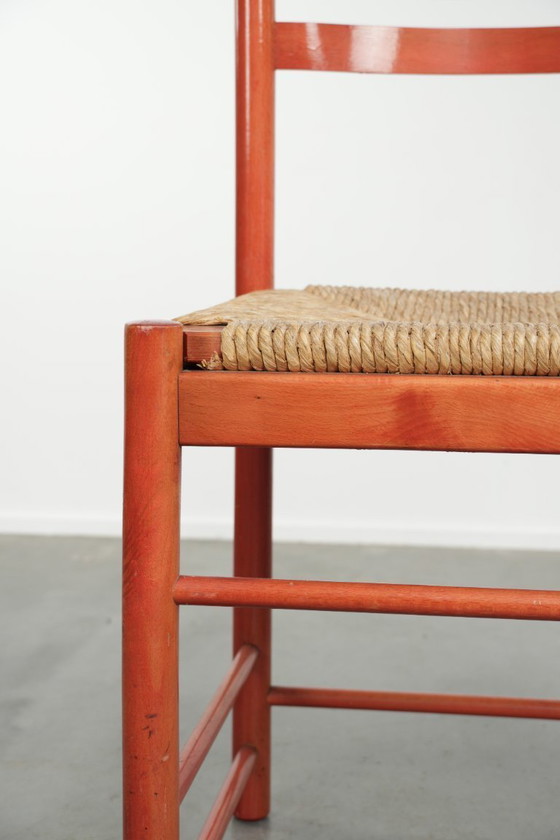 Image 1 of Schöner roter Vintage-Holzstuhl aus den 70er Jahren mit einer Sitzfläche aus geflochtenem Rohrgeflecht.