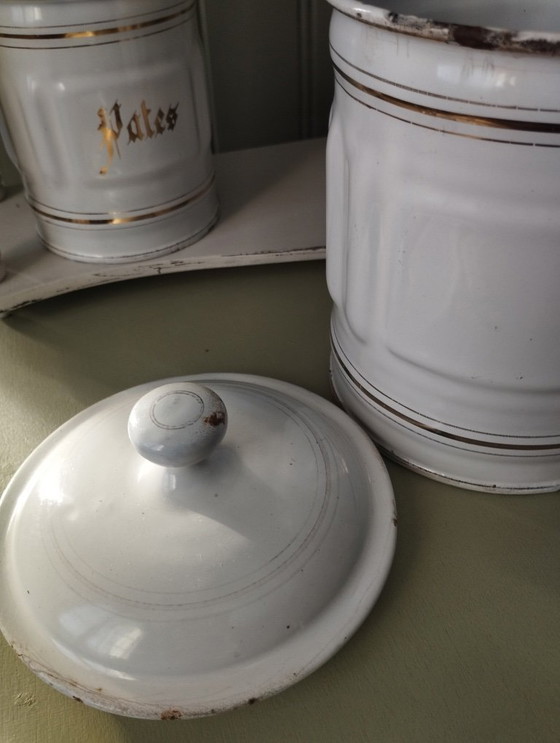 Image 1 of Antieke dozen gemaakt van wit geëmailleerd plaatmetaal met gegroefde randen en gouden versiering.